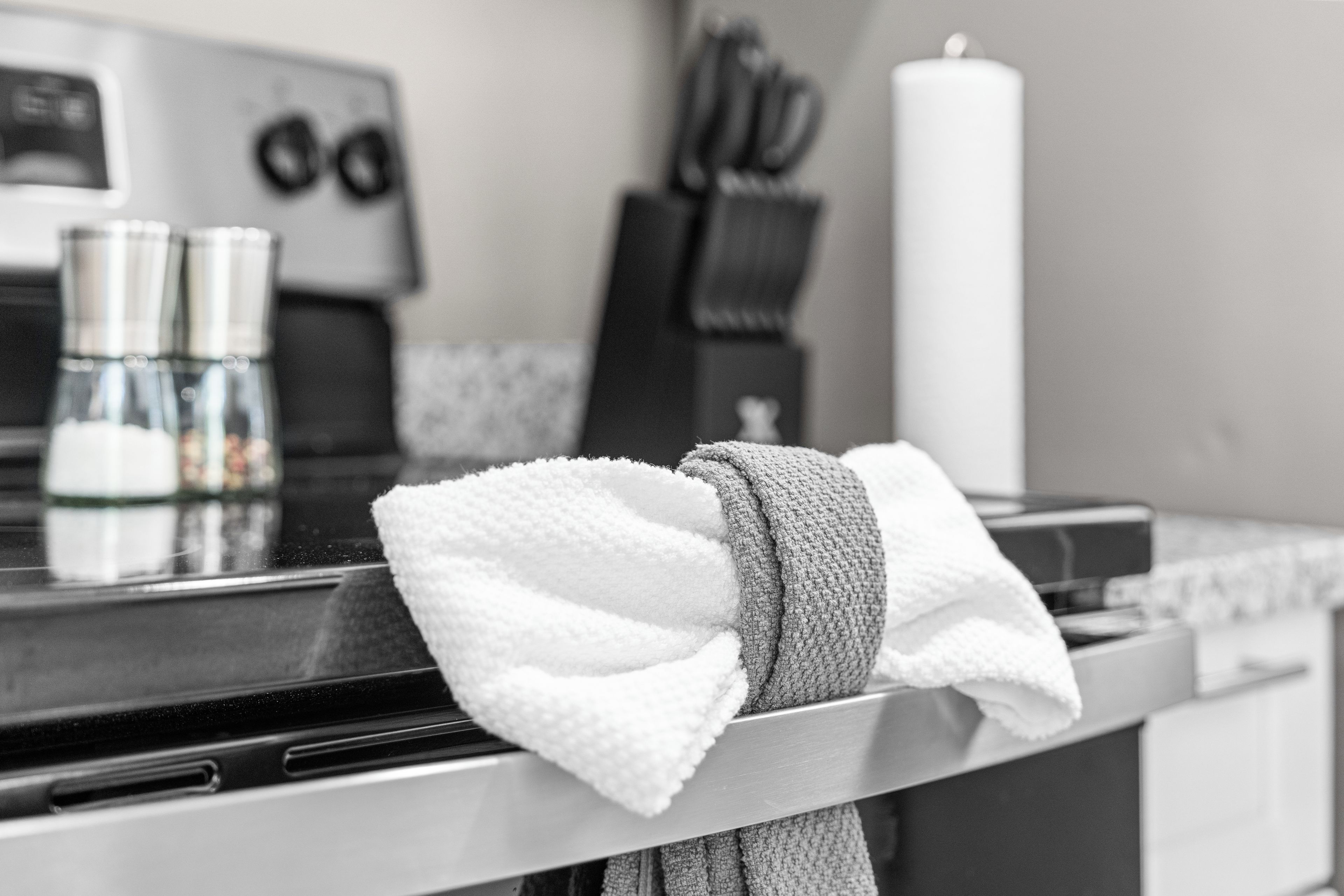 A kitchen with a stove, a kettle, and a roll of paper towels.