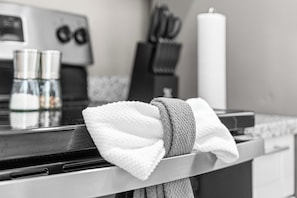 A kitchen with a stove, a kettle, and a roll of paper towels.