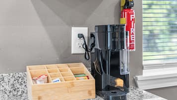 A coffee maker on a countertop, a wooden storage box with coffee pods, and a fire extinguisher on the wall.