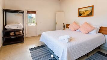 Quarto com cama, guarda-roupa, porta e um quadro na parede.