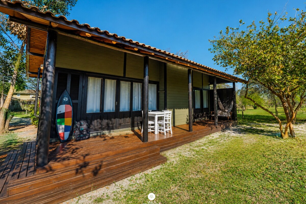 A wooden deck with a surfboard, a table, and chairs.