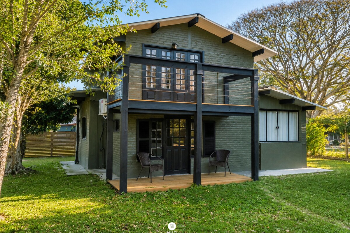 A two-story house with a balcony, a covered patio, and a lawn.