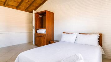 Quarto com cama de madeira, guarda-roupa e luminária pendente.