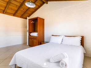 A bedroom with a wooden bed, a wardrobe, and a hanging light fixture.