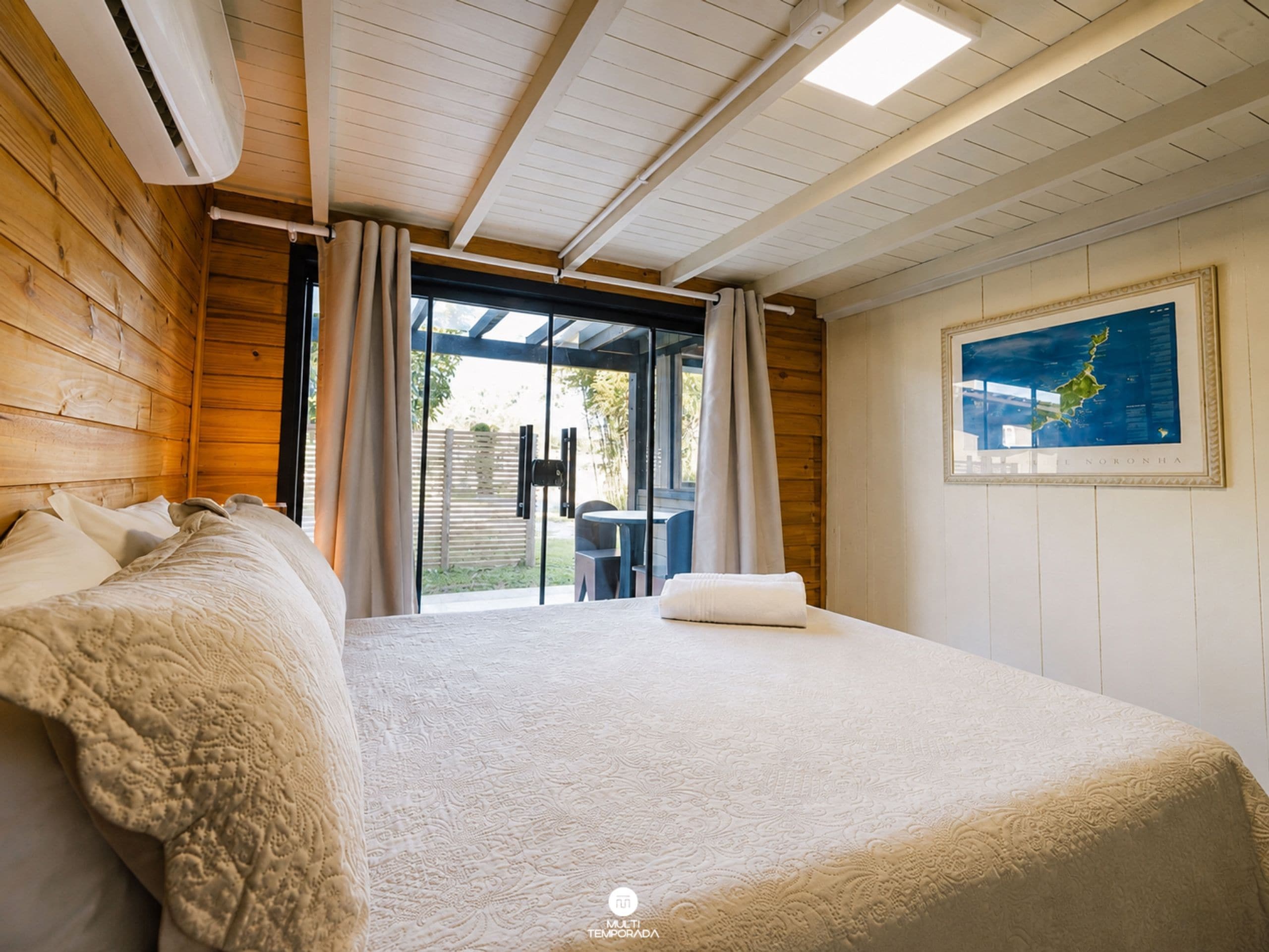 Un dormitorio con una cama grande, vistas al exterior y un mapa en la pared.