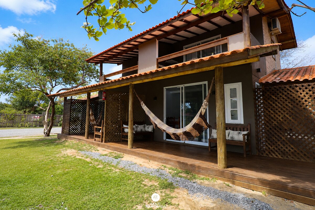 A two-story house with a covered porch, a hammock, and a view of the surrounding area.