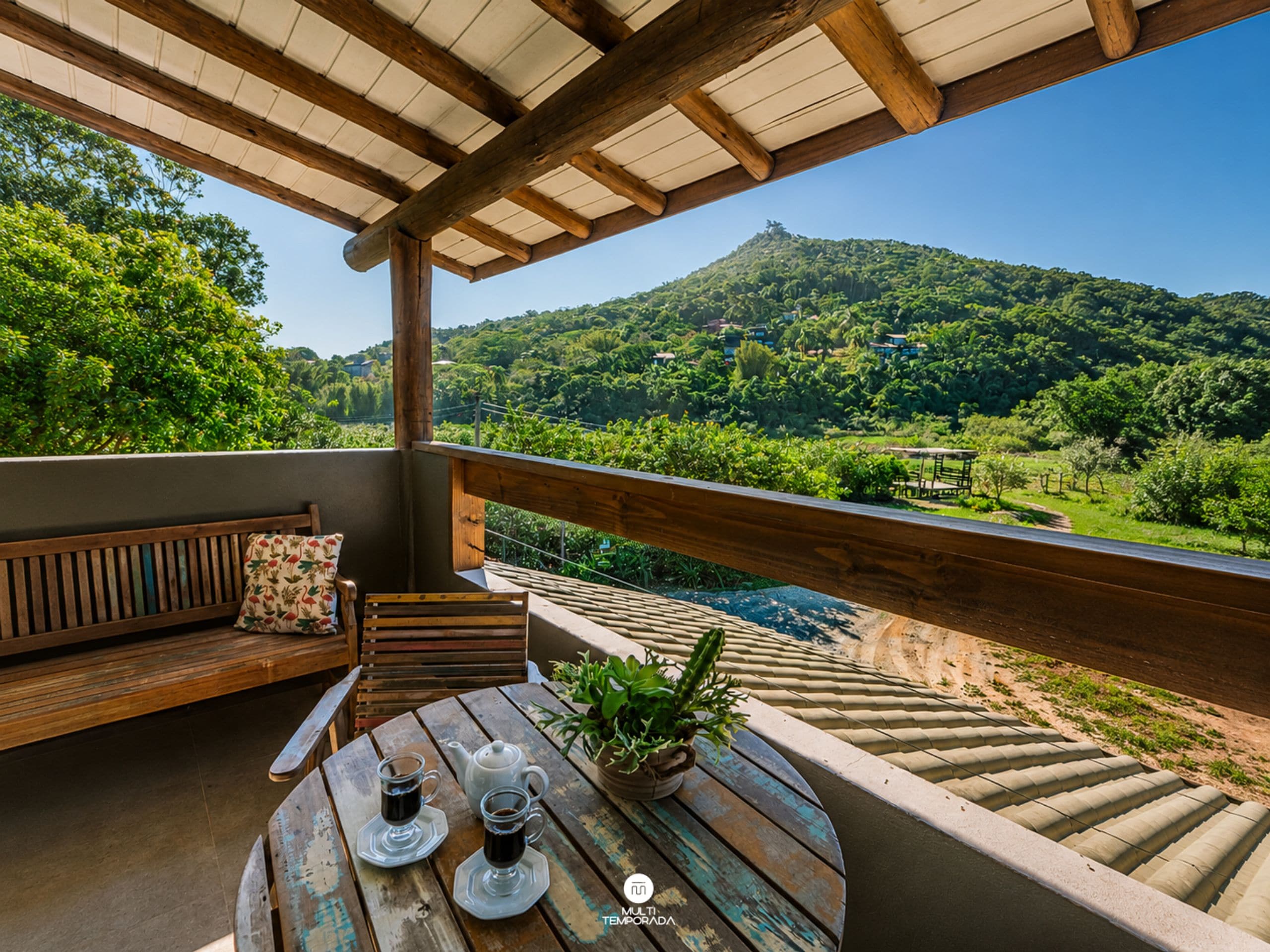 Eine Holzterrasse mit einem Tisch, zwei Kaffeetassen und einem Blumentopf.