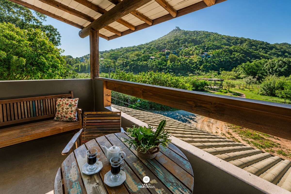 A wooden deck with a table, two cups of coffee, and a potted plant.