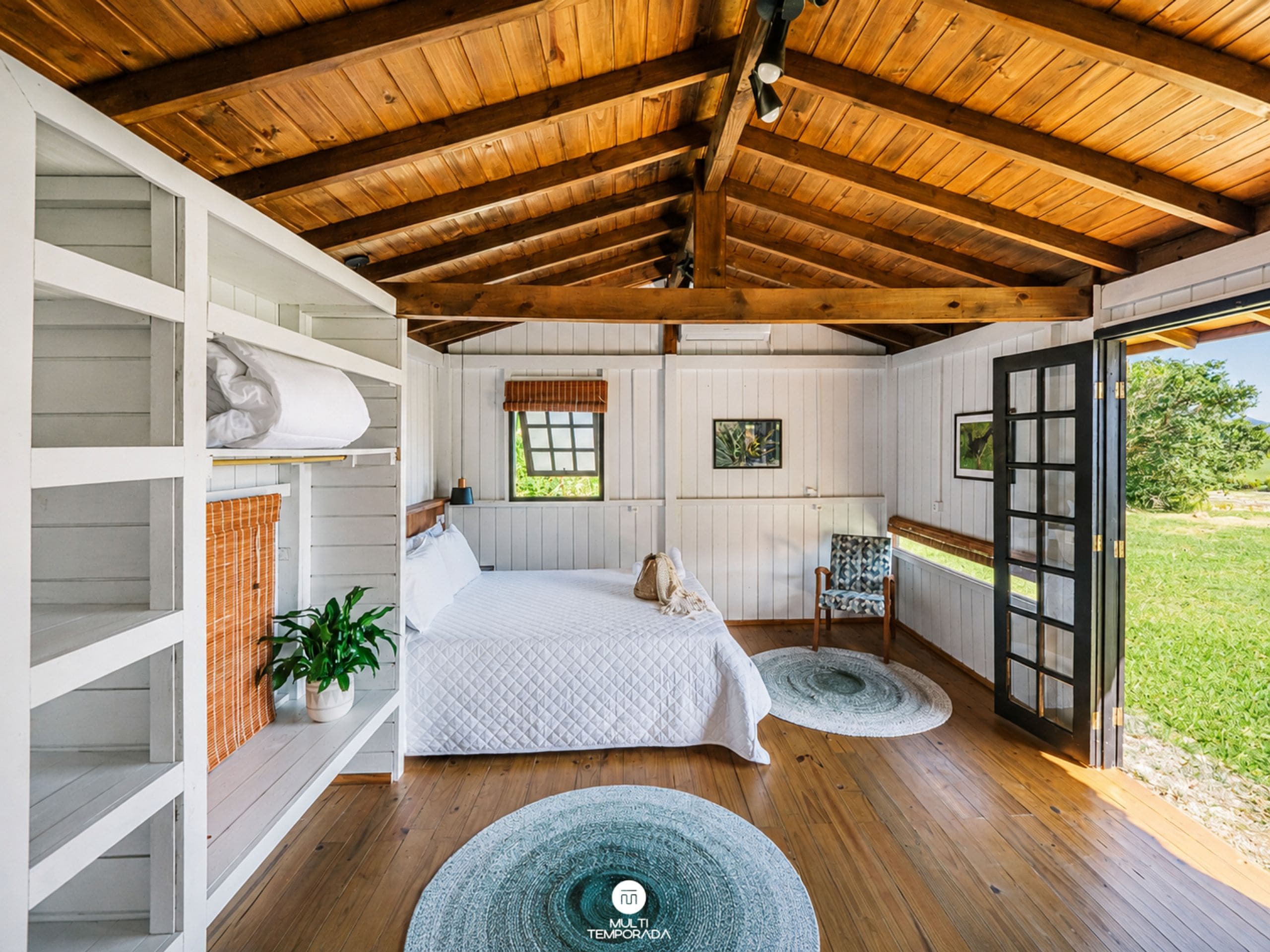 Un dormitorio con cama, una silla, un ventanal y vistas al exterior.
