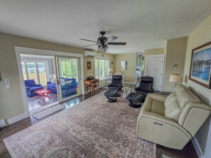 A spacious living room with a large rug, a beige sofa, a blue couch, and a ceiling fan. - Oceanfront house close to Acadia National Park! (Ellsworth)