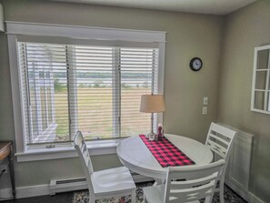 A dining area with a table, chairs, a lamp, and a view through the window. - Oceanfront house close to Acadia National Park! (Ellsworth)