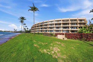 Ein Strandhotel mit mehreren Balkonen, einem gepflegten Rasen und Palmen.