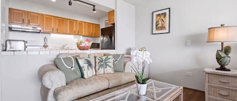 Ein Wohnzimmer mit einer Couch, einem Couchtisch und einer Küche im Hintergrund.