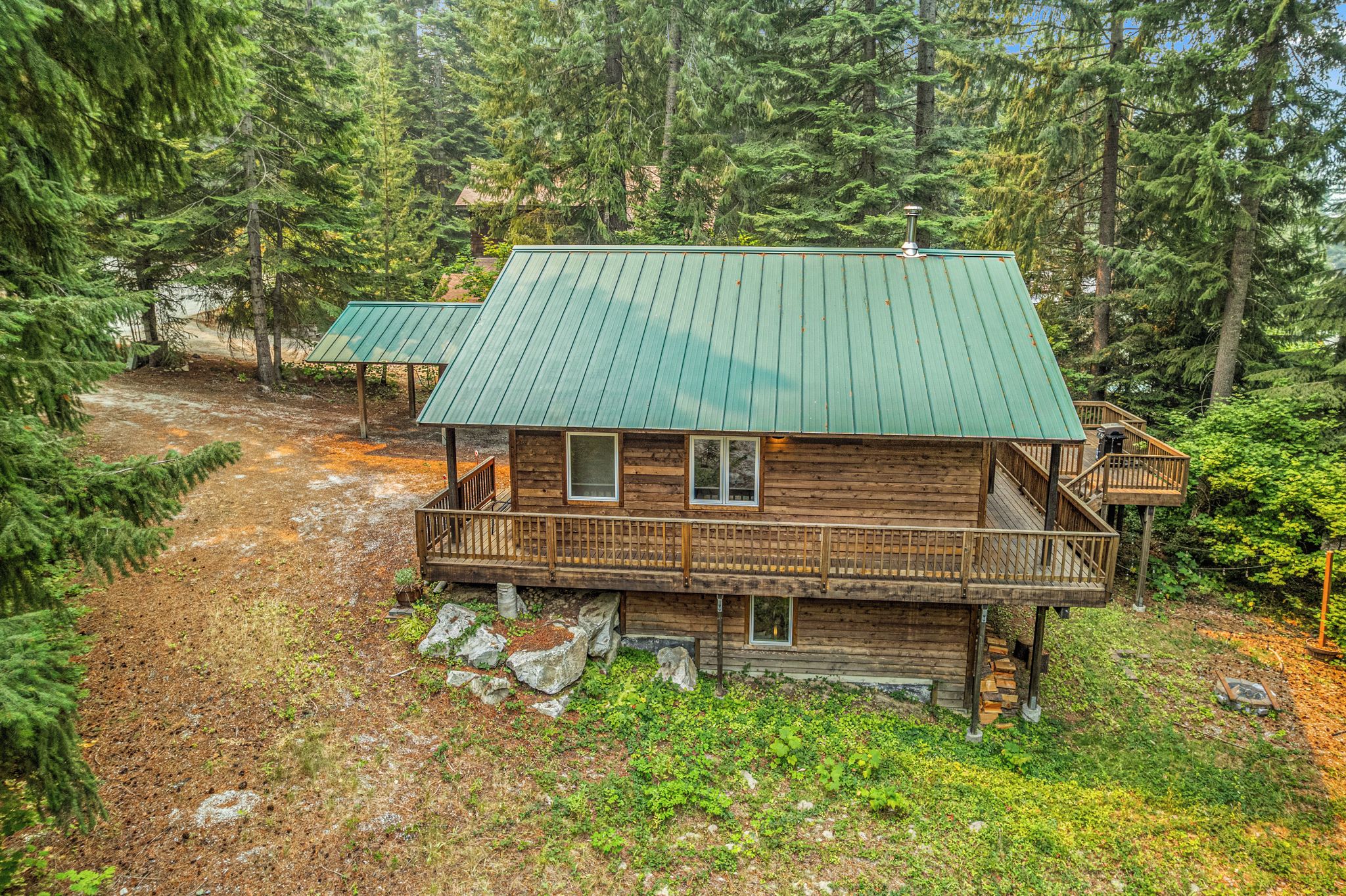 Une cabane dotée d’un toit végétalisé, d’une terrasse en bois et de fondations en pierre.