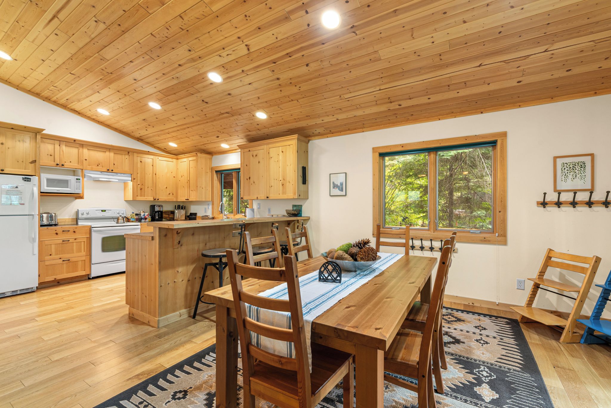 A modern kitchen with wooden cabinets, a central island, and a dining area with a table and chairs.