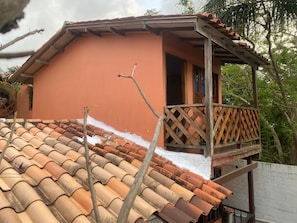 Una casa con tetto in tegole e un balcone con inferriata in legno.