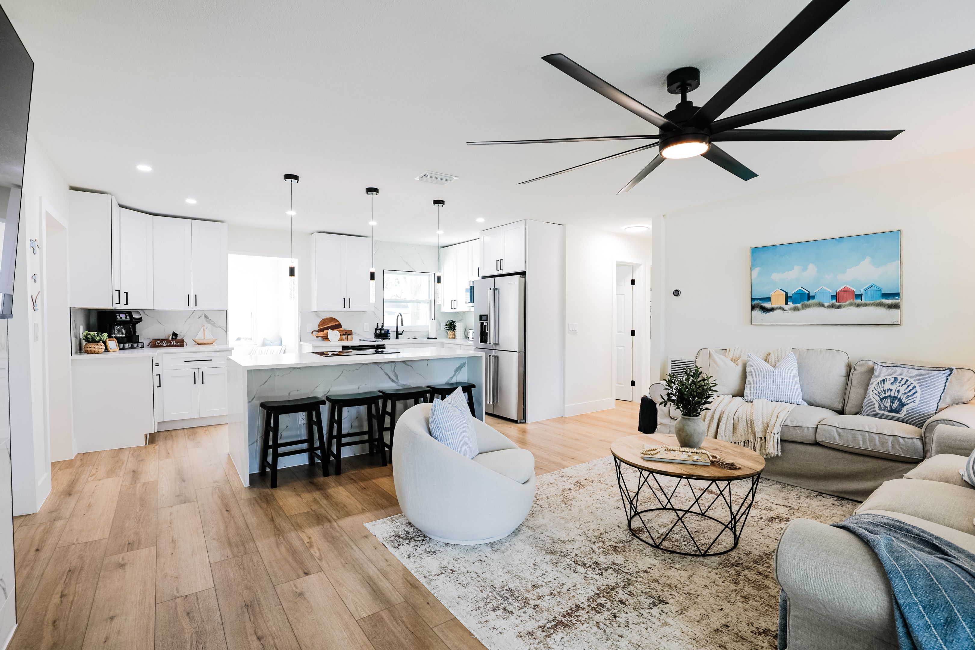 A modern kitchen with white cabinets, a central island, and a ceiling fan.