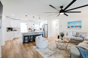 A modern kitchen with white cabinets, a central island, and a ceiling fan. - Beach, Bark and Bonfire - Spa/Firepit Home - Largo (Largo)