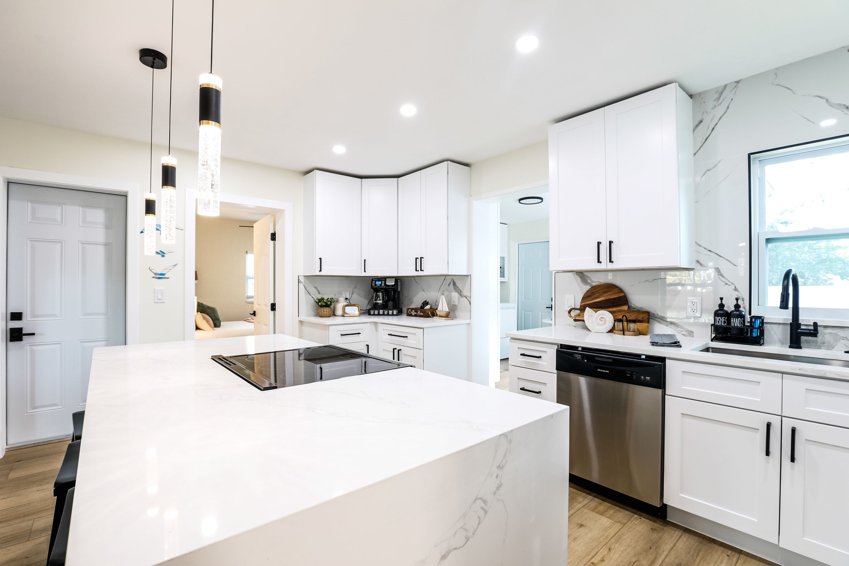 Une cuisine moderne avec des meubles blancs, un îlot central et un lave-vaisselle encastré.