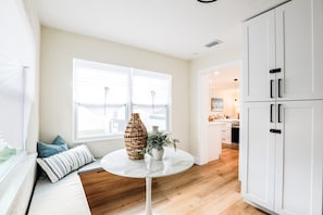A modern kitchen with white cabinetry, a round white table, and a bench with cushions. - Beach, Bark and Bonfire - Spa/Firepit Home - Largo (Largo)