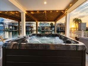 A hot tub with a wooden deck and a view of houses across a body of water. - Jamaica Beach | Bayfront | Hot Tub | Kayaks (Jamaica Beach)