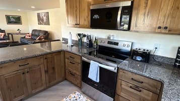 A kitchen with wooden cabinets, a stainless steel oven, and a granite countertop.