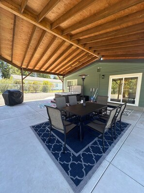 An outdoor patio with a wooden ceiling, a table with chairs, and a grill. - Coastal Retreat w/ Hot Tub Near Beach (Coos Bay)
