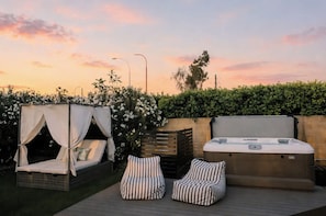 An outdoor patio with a hot tub, two striped lounge chairs, and a canopy bed. - Backyard Oasis, Pool, Spa, Game Room, BBQ (Scottsdale)