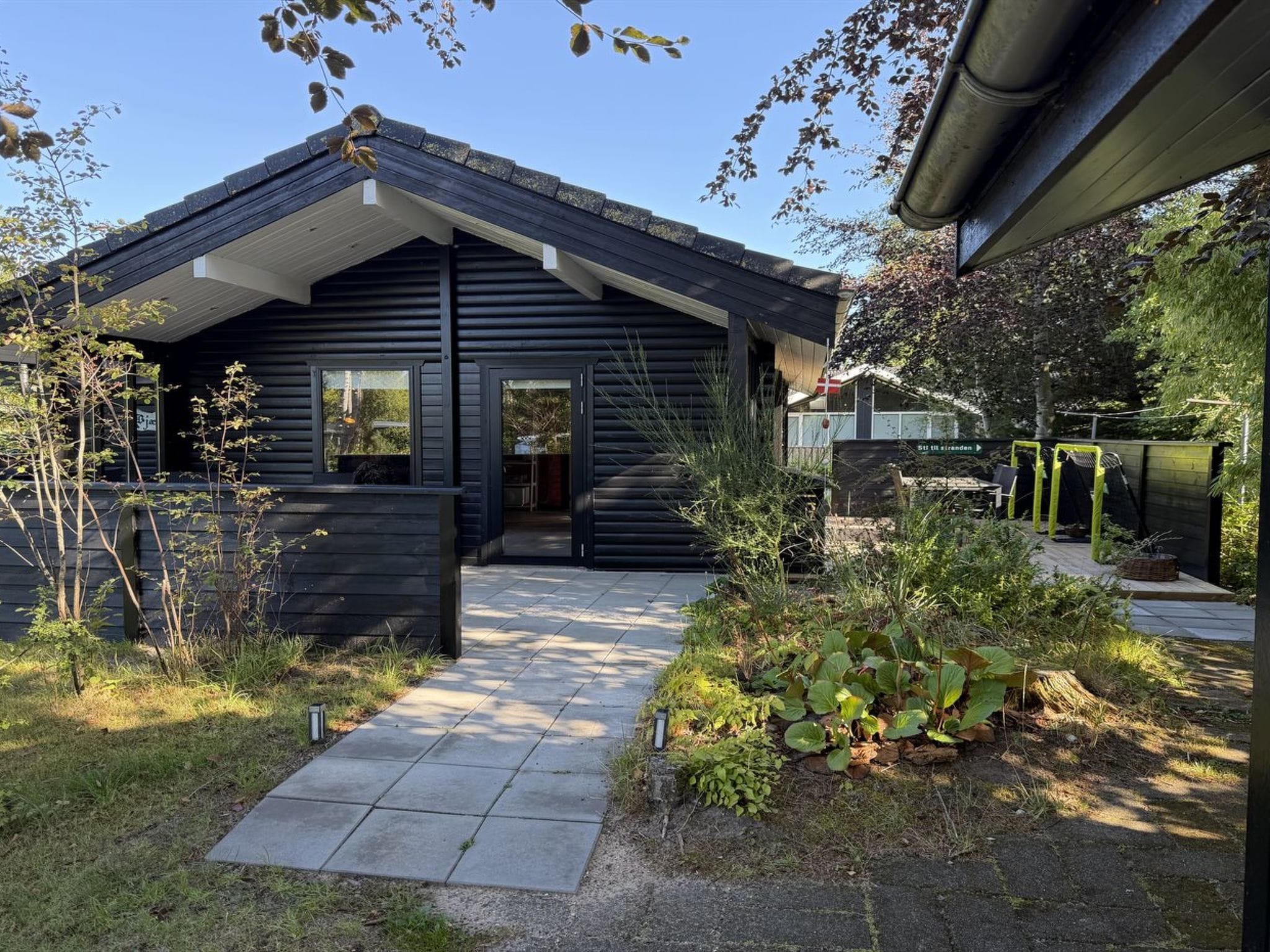 Ein modernes Haus mit dunkler Fassade, geneigtem Dach und befestigtem Zugang.