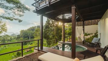 Zona junto a la piscina con vistas a un paisaje exuberante, una terraza de madera y una silla de descanso.