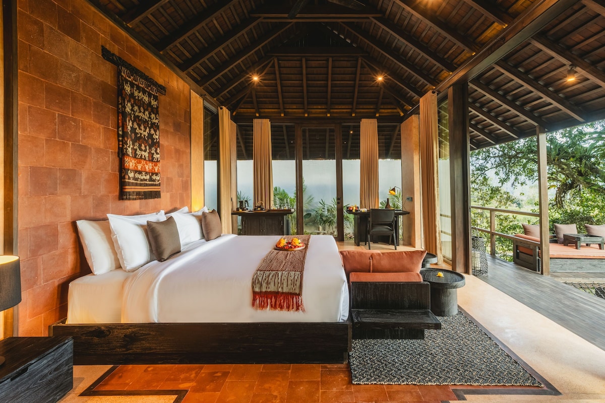 Un dormitorio amplio con una cama grande, un escritorio y vistas al exterior.