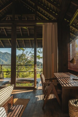 Una terraza de madera con mesa y sillas, con vistas a un paisaje exuberante.