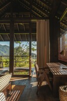 Una terraza de madera con mesa y sillas, con vistas a un paisaje exuberante.