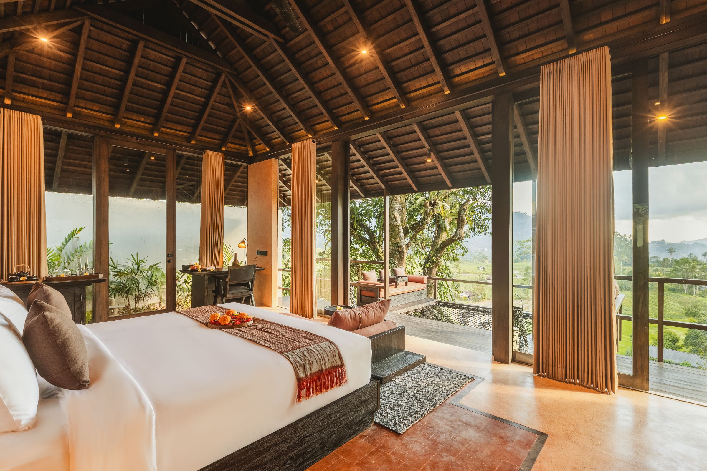 A spacious bedroom with a large bed, a desk, and a view of the outdoors.