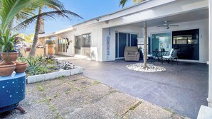 Una casa moderna con un porche cubierto, mobiliario de exterior y un pequeño jardín.