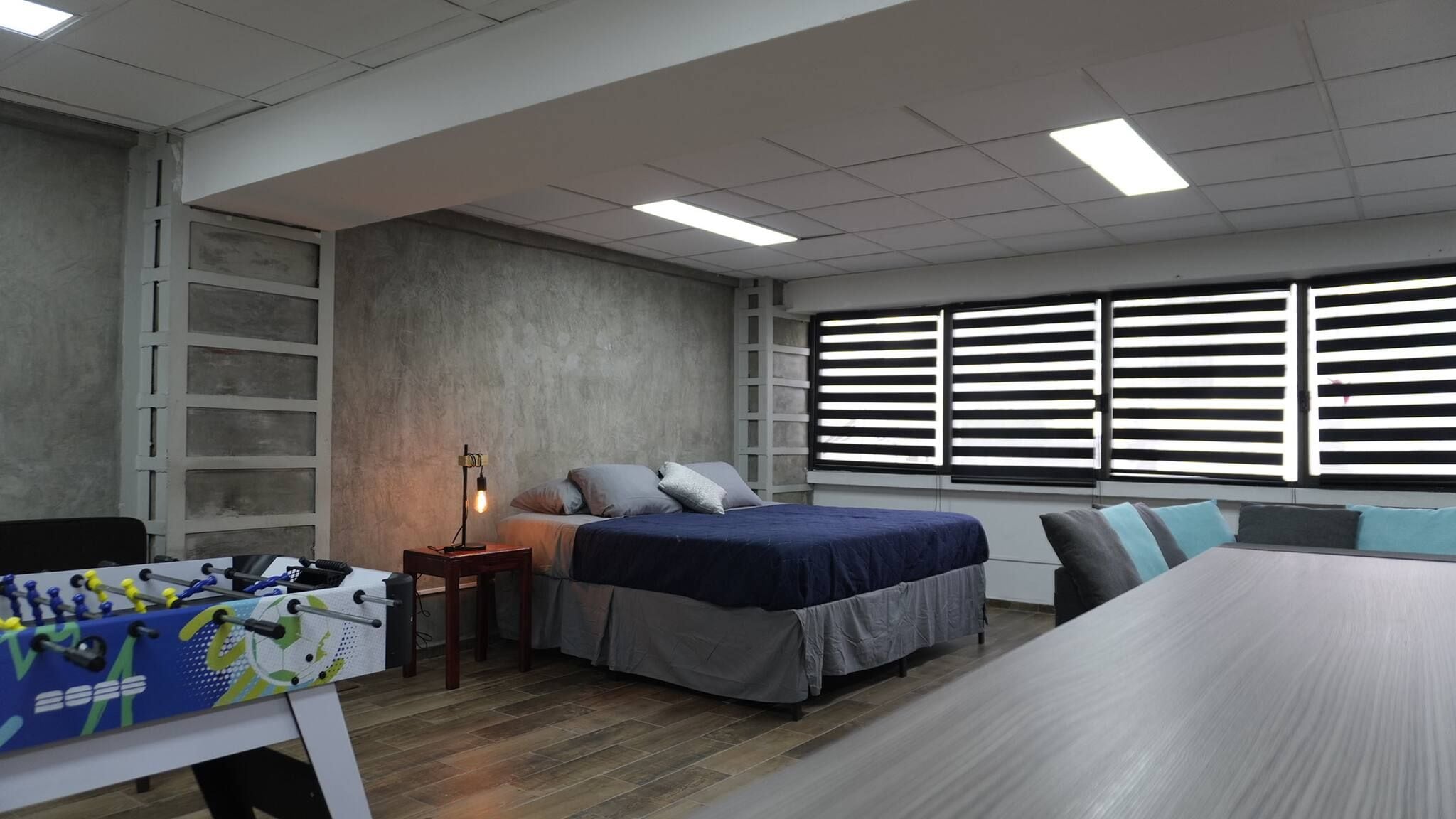A bedroom with a bed, bedside table, and a window with blinds.