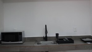 A kitchenette with a microwave, a sink, and a coffee maker. - Modern Loft King Bed, Wifi & Smart Lock (Mexico City)