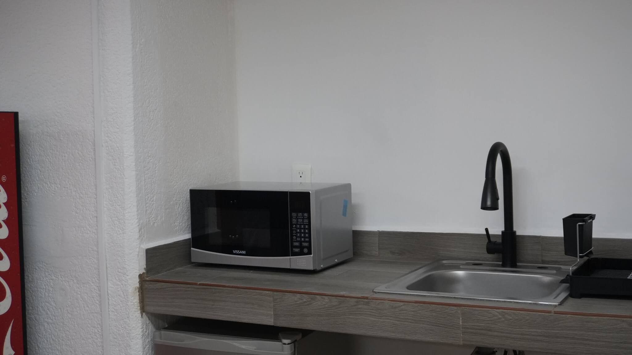 A kitchenette with a microwave, a sink, and a faucet.
