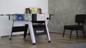 A foosball table with a 'New York' themed ball in a room with a concrete wall and a wooden floor. - Modern Loft King Bed, Wifi & Smart Lock (Mexico City)