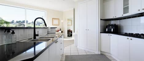 Una cocina moderna con armarios blancos, encimera negra y vistas al exterior.