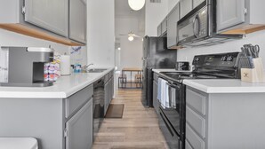 A modern kitchen with grey cabinets, a black refrigerator, a microwave, and a stove. - Stylish Mesa 2BR • Perfect for ASU Visits (Mesa)