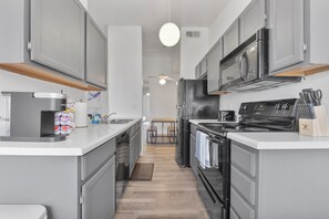 A modern kitchen with grey cabinets, a black refrigerator, a microwave, and a stove. - Stylish Mesa 2BR • Perfect for ASU Visits (Mesa)