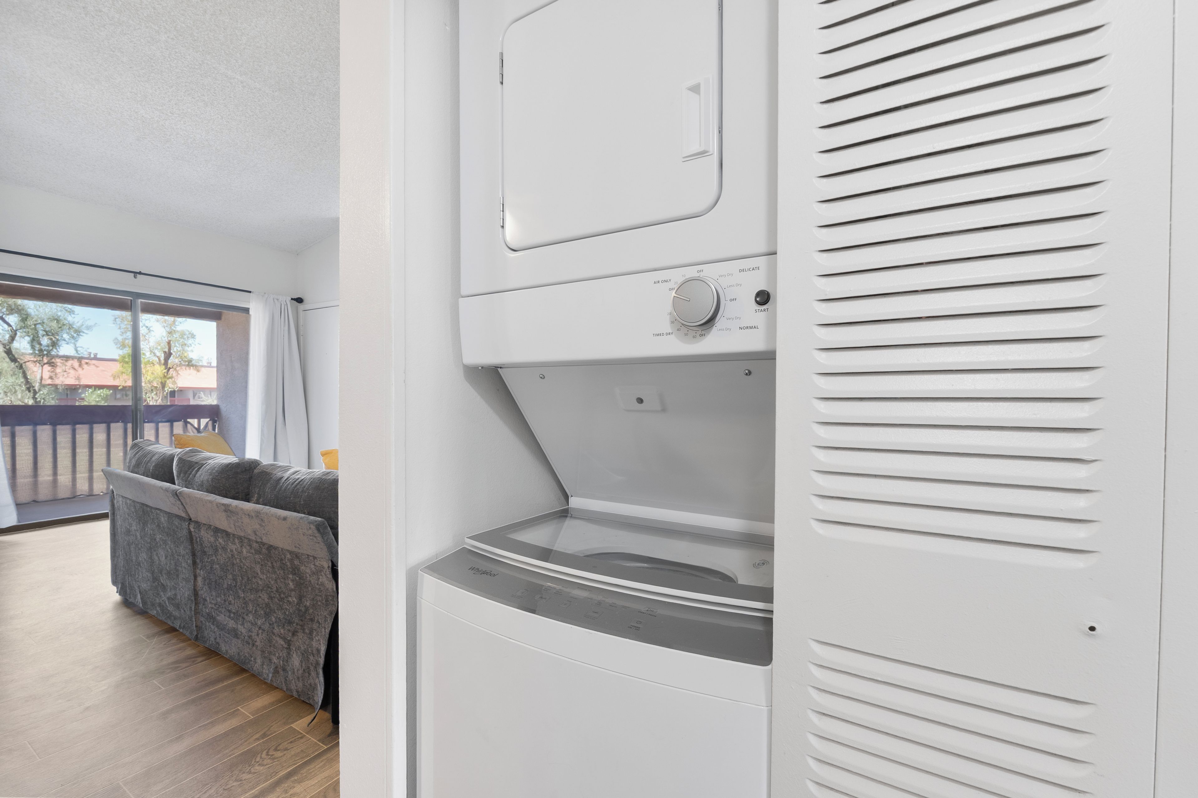 A modern laundry room with a large window, a sofa, and a washing machine.