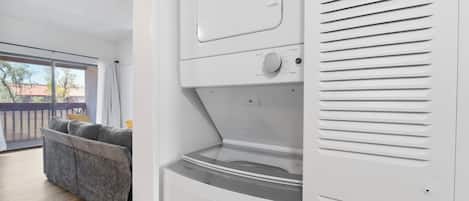A modern laundry room with a large window, a sofa, and a washing machine.