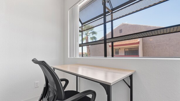 A room with a desk, a chair, a window with a view of buildings and palm trees. - Stylish Mesa 2BR • Perfect for ASU Visits (Mesa)