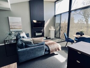 A modern living room with a sofa, a flat-screen TV, and a fireplace.