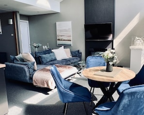 A modern living room with a sofa, chairs, a coffee table, and a flat-screen TV.