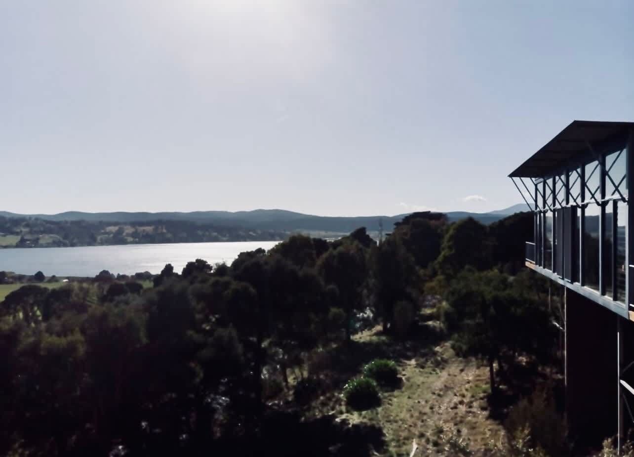 Ein Gebäude mit Blick auf einen See und Hügel.