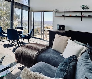 A modern living room with a large bed, a coffee table, and a balcony with a view.