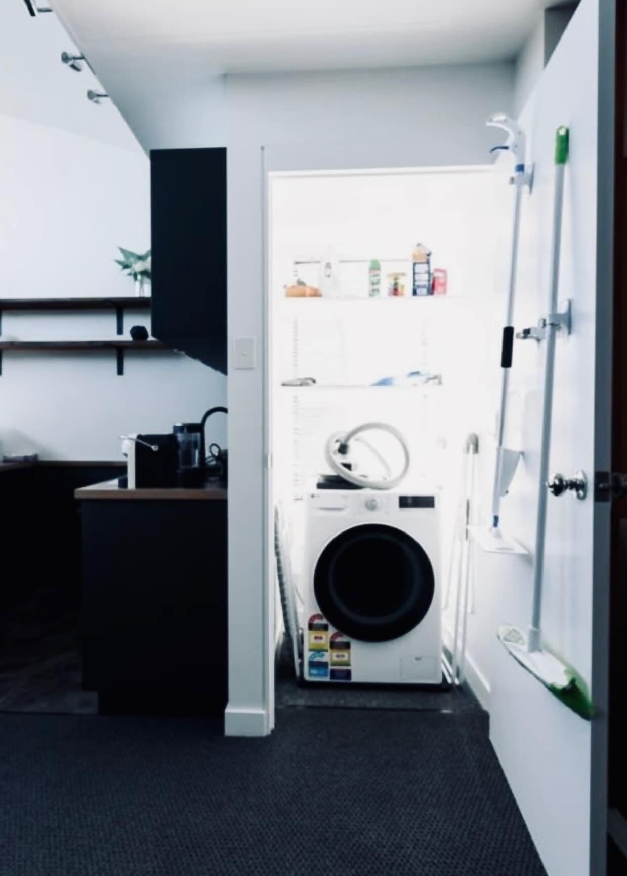 Ein kleiner Hauswirtschaftsraum mit Waschmaschine, Wäscheständer und Ablagefläche für Toilettenartikel.